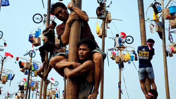 Participants react as they hold on to a greased pole during the Panjat Pinang competition for the celebration of Independence Day at Ancol Dreamland Park in Jakarta - Sputnik Узбекистан