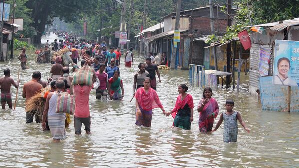 This file photo taken on August 17, 2017 shows Indian residents wading through flood waters in Balurghat in West Bengal. Torrential rain across India, Nepal and Bangladesh has killed at least 700 people since August 10, as the annual monsoon swept the north and east of the region. - Sputnik Узбекистан