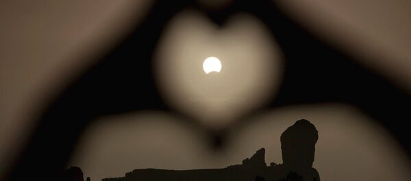 A woman makes a heart shape with her hands during a partial eclipse of the sun over the Roque Nublo mountain at the Canary Island of Gran Canaria A woman makes a heart shape with her hands during a partial eclipse of the sun over the Roque Nublo mountain at the Canary Island of Gran Canaria - Sputnik Узбекистан
