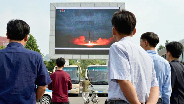 Северные корейцы наблюдают за новостным сообщением, показывающим запуск ракеты средней дальности - Sputnik Ўзбекистон