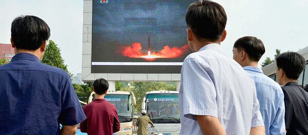 Северные корейцы наблюдают за новостным сообщением, показывающим запуск ракеты средней дальности Северные корейцы наблюдают за новостным сообщением, показывающим запуск ракеты средней дальности - Sputnik Ўзбекистон