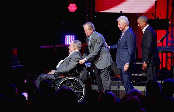 Former U.S. President George H.W. Bush is helped off the stage by George W. Bush as Bill Clinton and Barack Obama follow close behind during a concert at Texas A&M University - Sputnik Узбекистан