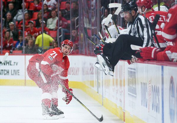 Detroit Red Wings center Dylan Larkin (71) clears the puck as linesman Michel Cormier (76) jumps out of the way during the second period against the Washington Capitals at Little Caesars Arena - Sputnik Узбекистан