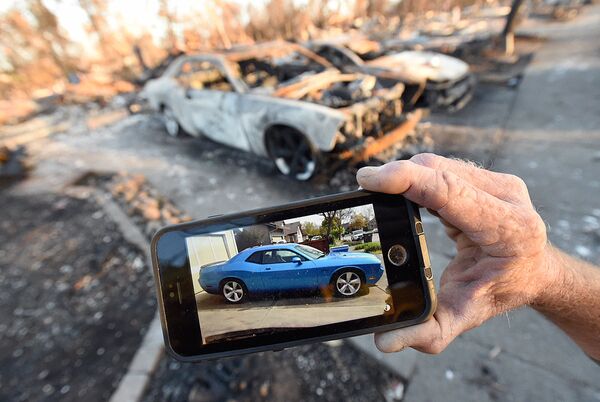 Car collector Gary Dower holds up a photo showing his 2010 Dodge Challenger Limited Edition SRT8 before it burned at his home in Santa Rosa, California on October 20, 2017 - Sputnik Узбекистан