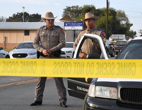 State troopers guard the entrance to the First Baptist Church (back) after a mass shooting that killed 26 people in Sutherland Springs, Texas on November 6, 2017. A gunman wearing all black armed with an assault rifle opened fire on a small-town Texas church during Sunday morning services, killing 26 people and wounding 20 more in the last mass shooting to shock the United States. - Sputnik Узбекистан