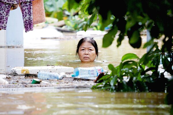 Женщина пробирается через затопленную улицу во Вьетнаме после тайфуна Дамри - Sputnik Узбекистан