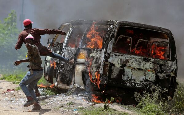 Сторонники кенийского оппозиционного движения Национальный суперальянс возле горящего автомобиля в Эмбакаси, Кения - Sputnik Узбекистан