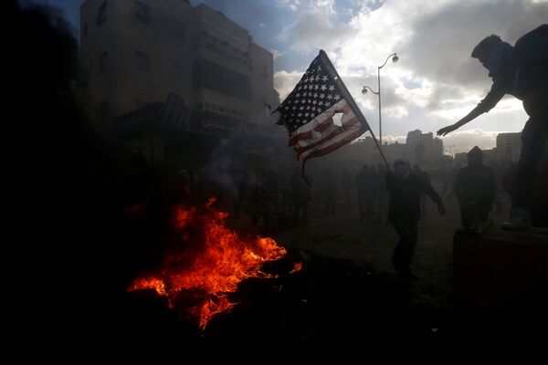 Палестинцы жгут американский флаг во время столкновений с израильской полицией в связи с протестами против решения Дональда Трампа признать Иерусалим столицей Израиля - Sputnik Узбекистан