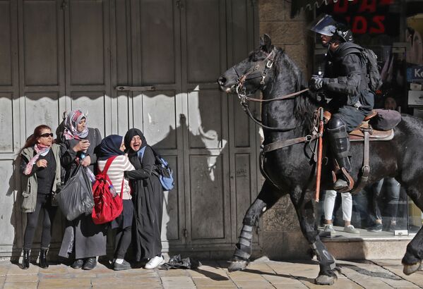 Испуганные женщины рядом с вооруженным израильским полицейским в Восточном Иерусалиме - Sputnik Узбекистан