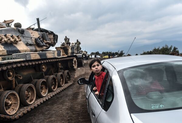 Девочка наблюдает из окна автомобиля, как танки и солдаты турецкой армии собираются у сирийской границы в городе Хасса, куда власти Турции перебросили свой спецназ - Sputnik Узбекистан