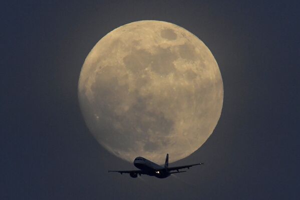 Самолет на фоне полной луны в небе над Лондоном, Великобритания - Sputnik Узбекистан