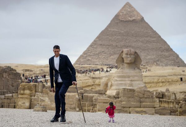 Самый высокий человек в мире Султан Кесен и самая низкая женщина в мире индианка Джоти Амджи на фоне пирамид Гизы в Египте - Sputnik Узбекистан