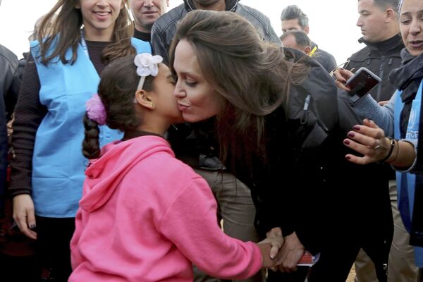 Посол доброй воли ООН актриса Анджелина Джоли целует сирийскую девочку во время визита в лагерь сирийских беженцев в городе Макфрак, Иордан - Sputnik Узбекистан