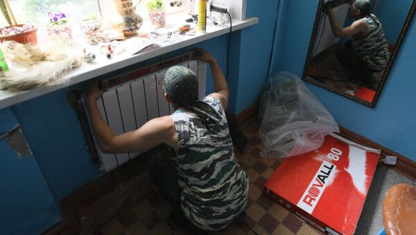 Рабочий устанавливает радиатор отопления в подъезде жилого дома - Sputnik Узбекистан