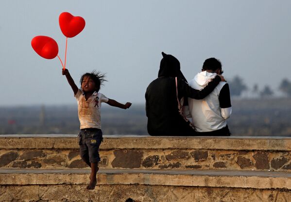 Ребенок с шариками-сердечками и пара на улице Мумбаи в День всех влюбленных - Sputnik Узбекистан