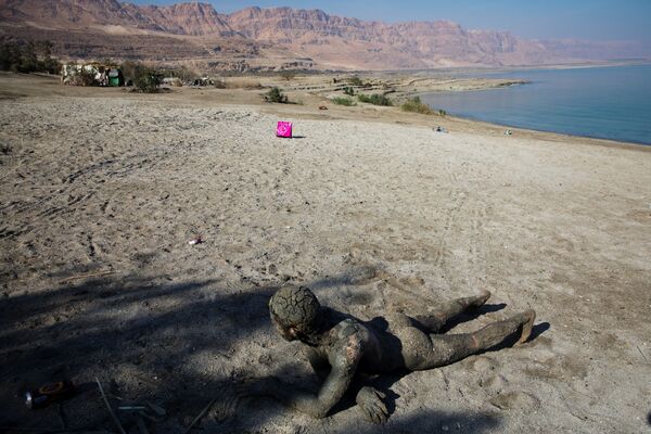 Мужчина, покрытый лечебной грязью на берегу Мертвого моря, недалеко от Меццока Драго, Израиль, Западный берег - Sputnik Узбекистан