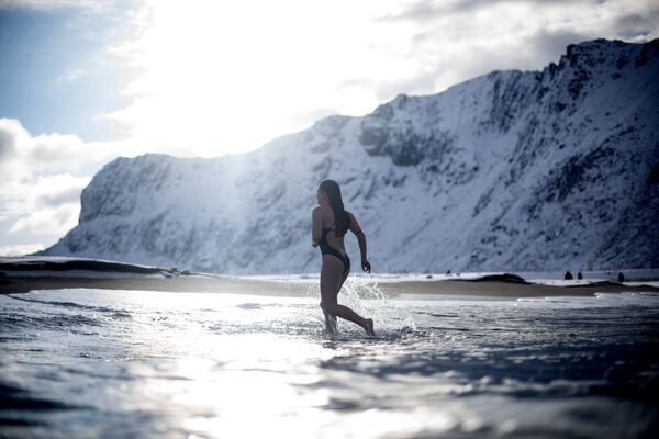 Молодая женщина ныряет в воду на Лофотенских островах в Норвегии при температуре воздуха -5 и температуре воды +4 - Sputnik Узбекистан
