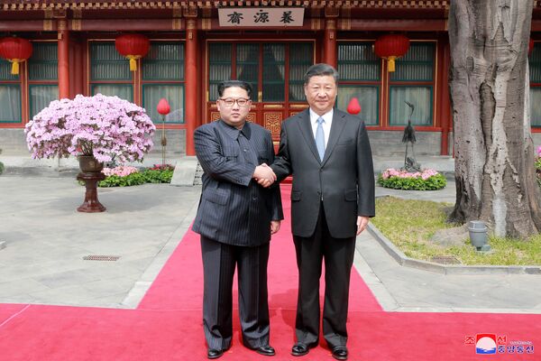 Северокорейский лидер Ким Чен Ын пожимает руку китайскому президенту Си Цзиньпину, во время его неофициального визита в Пекин. - Sputnik Узбекистан