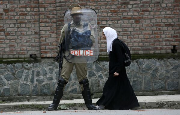 Мусульманская студентка идет мимо индийского полицейского во время протеста против недавних случаев изнасилования в городе Сринагар в Кашмире, Индия - Sputnik Узбекистан