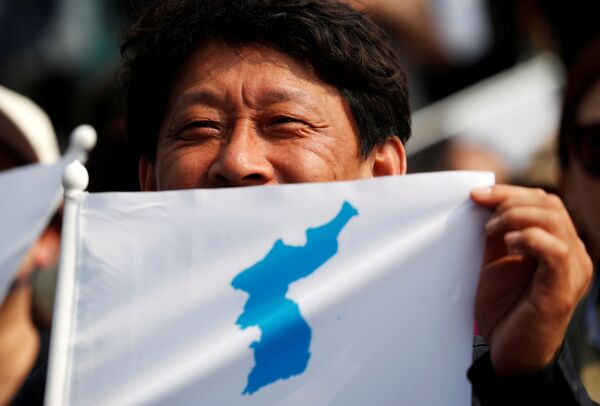 Мужчина показывает флаг Корейской империи перед приветственной церемонией в деревне Пханмунджом в демилитаризованной зоне, разделяющей две Кореи - Sputnik Узбекистан