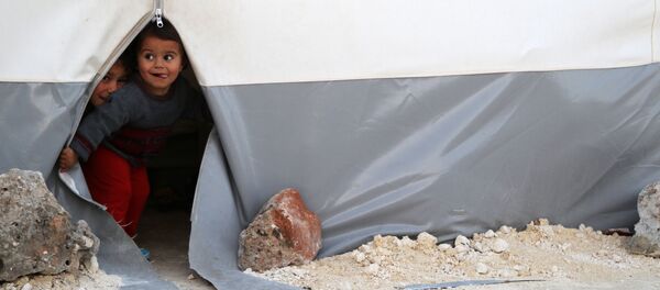 Дети выглядывают из палатки временного лагеря для перемещенных лиц из Восточной Гуты в сирийской провинции Идлиб - Sputnik Узбекистан