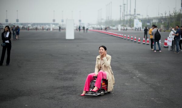Женщина на самодельном мини-транспортном средстве во время автосалона в Шанхае - Sputnik Узбекистан