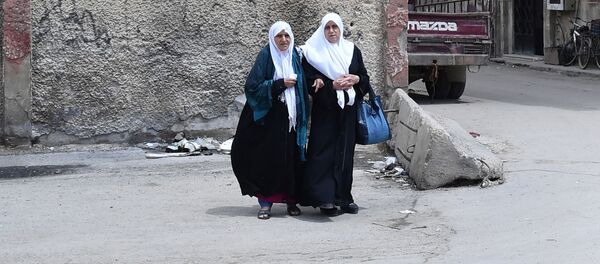 Женщины переходят дорогу в районе бывшего лагеря палестинских беженцев Ярмук в южном пригороде Дамаска Женщины переходят дорогу в районе бывшего лагеря палестинских беженцев Ярмук в южном пригороде Дамаска - Sputnik Узбекистан