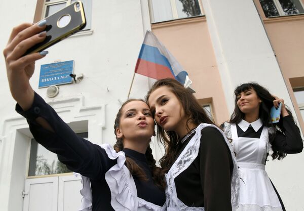 Выпускницы делают селфи у входа в школу №47 во время празднования последнего звонка в городе Чите - Sputnik Узбекистан