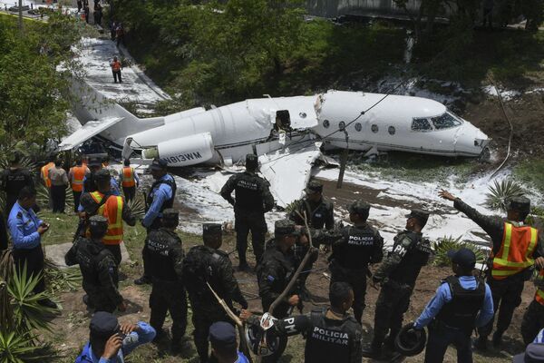 Полиция и спасатели работают у самолета, выкатившегося за пределы взлетно-посадочной полосы и развалившегося на части после приземления в международном аэропорту Тонконтин в Тегусигальпе, Гондурас - Sputnik Узбекистан