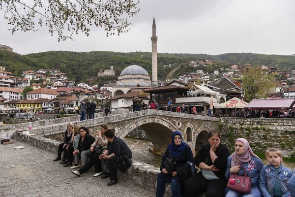 Люди сидят рядом с каменным мостом с видом на город Призрен, Косово - Sputnik Узбекистан