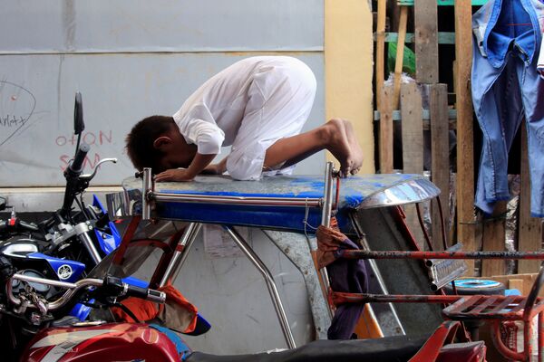 Мальчик молится на мотоциклетной кабине во второй день Рамадана у храма в Маниле, Филиппины - Sputnik Узбекистан
