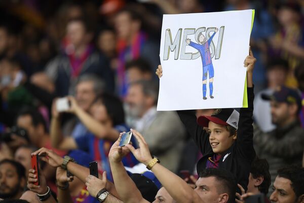 Юный болельщик с плакатом с изображением форварда Барселоны Лионеля Месси перед матчем между Барселоной и Реал Мадридом в Барселоне - Sputnik Узбекистан