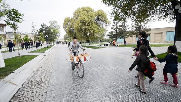 Молодой человек везет лепешки на велосипеде - Sputnik Узбекистан