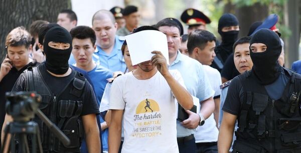 Полицейские и подозреваемый в убийстве фигуриста Дениса Тена Нуралы Киясов (в центре) на месте преступления в Алматы. - Sputnik Узбекистан