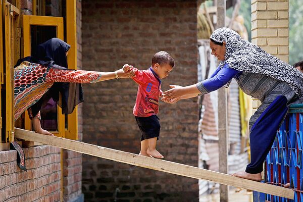 Женщины и ребенок покидают дом после внезапного наводнения в Тайлбале, на окраине Шринагара. - Sputnik Узбекистан