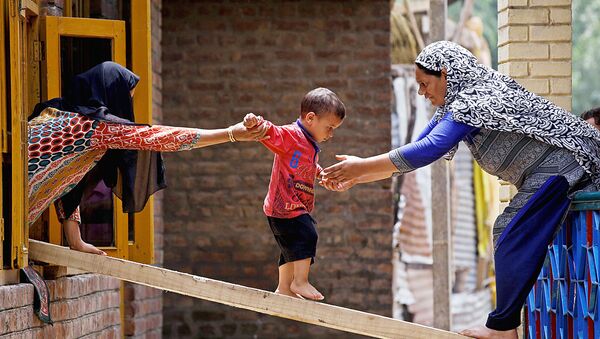 Женщины и ребенок покидают дом после внезапного наводнения в Тайлбале, на окраине Шринагара  - Sputnik Узбекистан