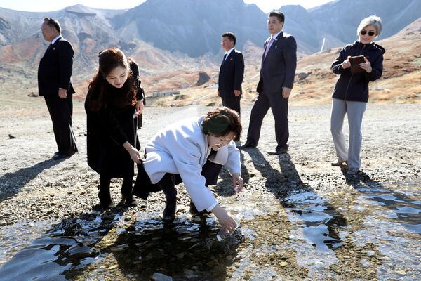 Ким Чен Сук наполняет пластиковую бутылку водой из Небесного озера МТ. Пэкту, Северная Корея - Sputnik Узбекистан