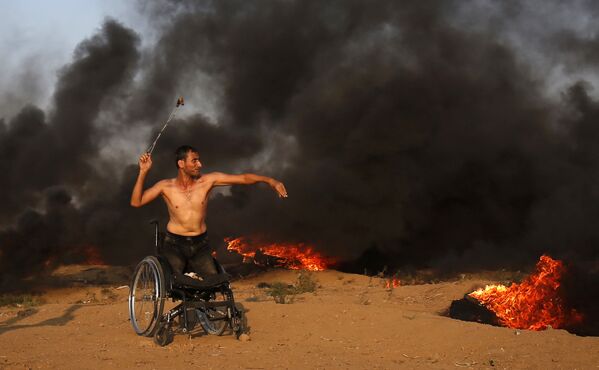 Палестинец на инвалидной коляске бросает камень в сторону израильских военных  - Sputnik Узбекистан