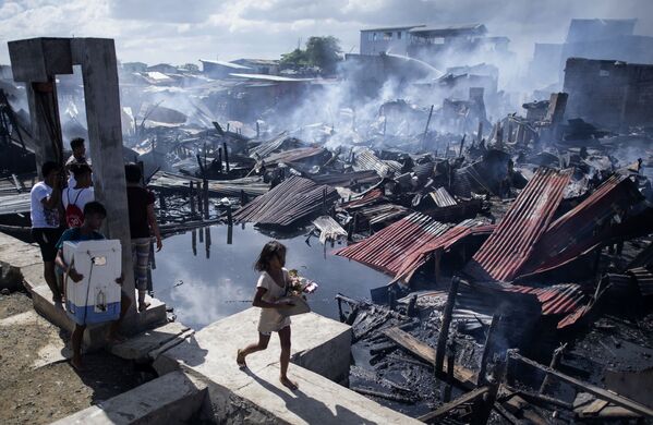 Девочка проходит мимо разрушенных домов после пожара, охватившего район трущоб в Навотасе, Филиппины. 8 ноября 2018 года - Sputnik Узбекистан
